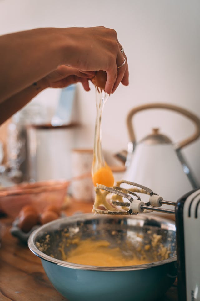 Image of a baker adding eggs to a bowl of batter
